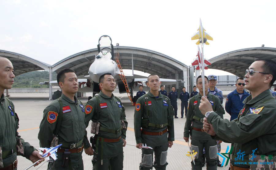 ↑艦載航空兵某部司令員戴明盟向飛行員演示空中飛行注意事項(xiàng)。